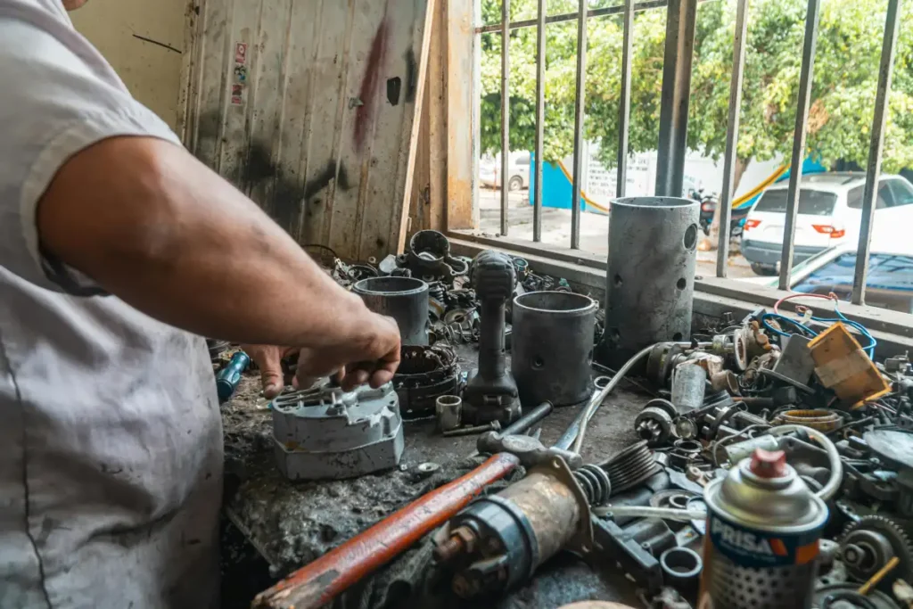 Mekanik merapikan berbagai suku cadang otomotif di bengkel yang penuh peralatan dan komponen kendaraan